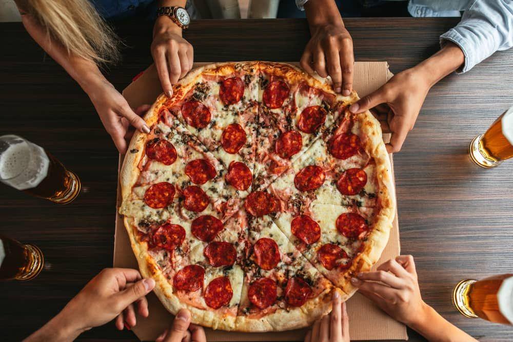 Group enjoying pizza and beer during the Vegas Pot & Pizza Tour, featuring stops at top dispensaries and a local pizzeria.